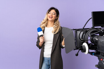 Reporter teenager girl holding a microphone and reporting news isolated on purple background with...