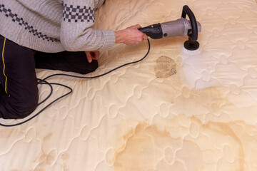 a man cleans a dirty mattress with an electric brush