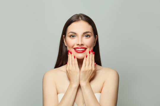 Nice brunette woman showing her hands with red manicured nails. Body care and manicure concept