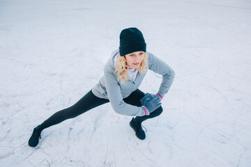 Fototapeta na wymiar Woman is stretching outside in front of a frozen lake. Sport in winter. Workout in snow. Activities in winter when it's cold 