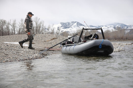 fly fisherman walking to pontoon raft on a river