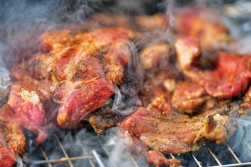 Delicious piece of pork neck roasting on the grill during preparation. Closeup macro of Pork steak meat with smoke on barbecue grill. 