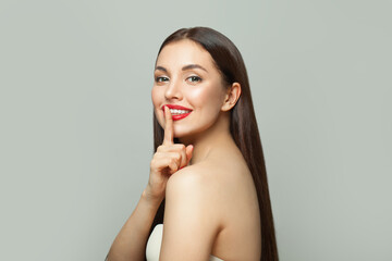 Happy young woman holding finger near lips. Secret and silence concept