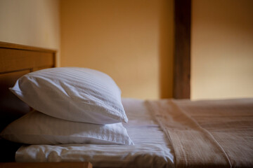 bed in the bedroom, bed in hotel room, pillows in the hotel, fresh clean linen on the bed, a hotel room ready for guests, service in a motel - obrazy, fototapety, plakaty