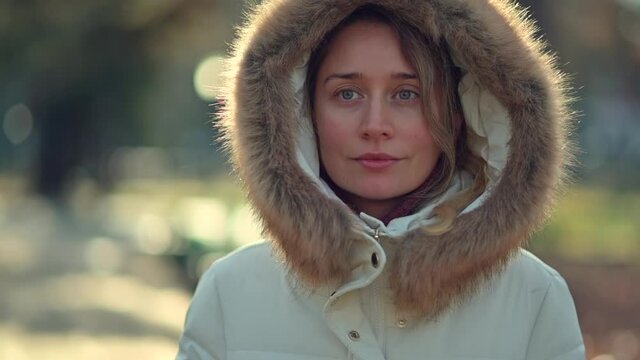 Happy woman wearing white winter coat  resting outside in the sun