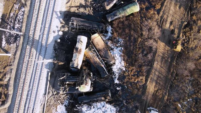 A train wreck on the railway, scattered cisterns soiled with fuel oil. Aerial view of the accident - a crash with damaged wagons lying next to the rails. Rescuers carry out repair work.