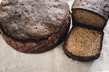 Rye bread loaf on linen textile background. Homemade sourdough, whole grain bread. Healthy lifestyle concept.