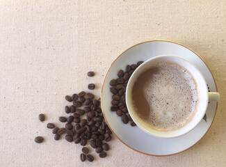 Cup of coffee and grains scattered around. In morning or during break from work and have cup of aromatic coffee. It's nice to enjoy wonderful taste. Rest and free time during the day. Pale background