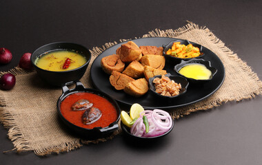 bafle or bati is popular main course dish in India served with dal daal brinjal curry jaggery gud and clarified butter or ghee