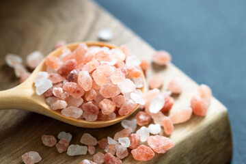 Pink Himalayan salt in the wooden spoon on the table. - obrazy, fototapety, plakaty