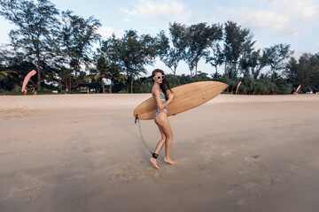 Slim brave adult woman wearing multicolored bikini and sunglasses preparing to swim on a surfboard. Good experienced woman. Extreme sport. Vacation concept