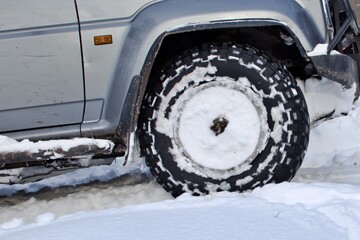blurred motion of front wheel of vehicle driving on snow winter road