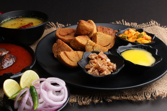 bafle or bati is popular main course dish in India served with dal daal brinjal curry jaggery gud and clarified butter or ghee