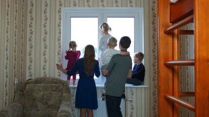 A large and friendly family at the window during quarantine and waved.