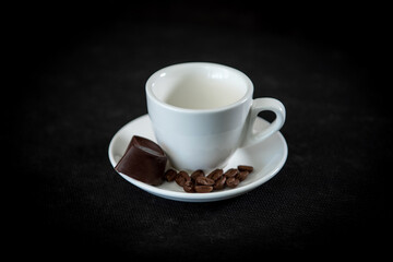White cup of coffee on a saucer with coffee beans and marshmallows. Espresso. Close-up.