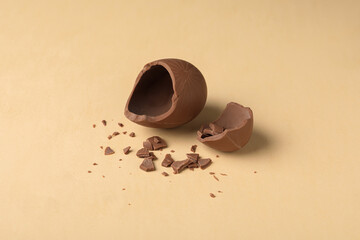 Broken milk chocolate egg on beige background