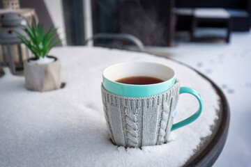 A cup of hot tea on the snowy garden terrace at winter