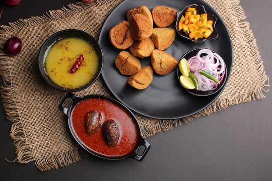 bafle or bati is popular main course dish in India served with dal daal brinjal curry jaggery gud and clarified butter or ghee