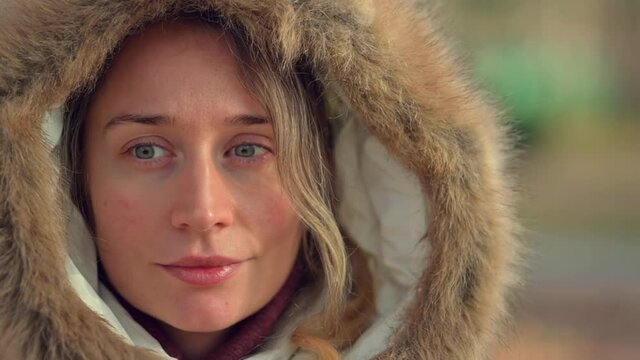 Happy woman wearing white winter coat  resting outside in the sun