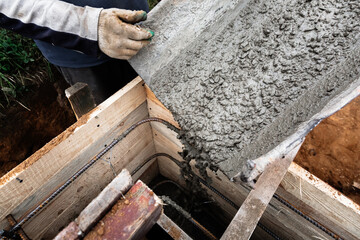 The concrete mixer loads the concrete through a chute into a timber formwork with metal...
