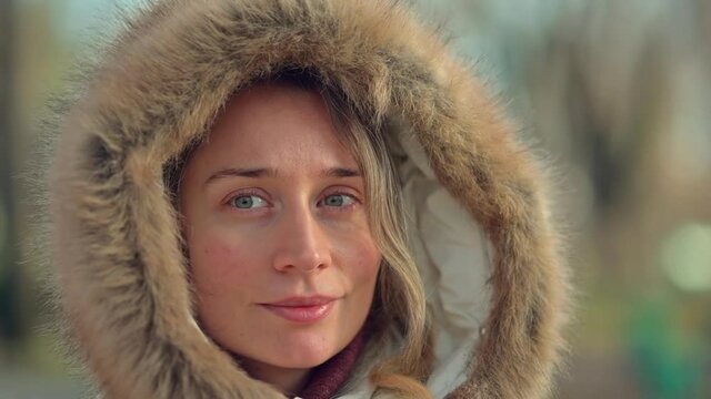 Happy woman wearing white winter coat  resting outside in the sun