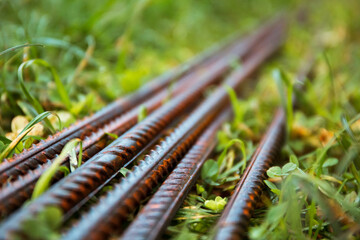 Reinforced steel bars on green grass background of construction site with copy space. Metal base of reinforced concrete walls and buildings. Structure material. Close-up of smooth sturdy steel rods