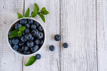 Bowl of fresh blueberries on wooden table. Organic food blueberries and mint leaf for healthy lifestyle. Top view