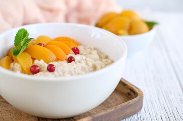 Delicious porridge with apricots and berries. Fresh breakfast served on grey table