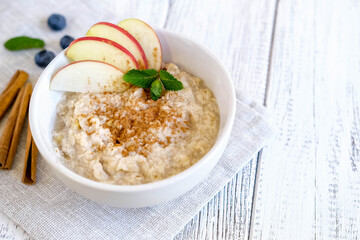 Delicious porridge with apple and cinnamon. Fresh natural breakfast served on wooden table