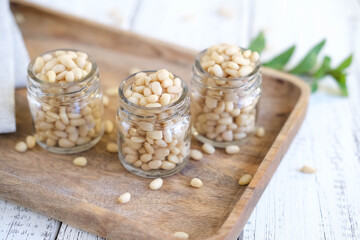 Delicious pine nuts in glass jars on wooden tray. Healthy food and nutrition concept