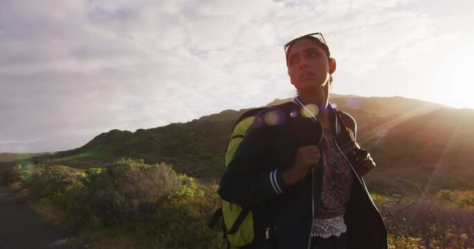 Mixed race woman walking on road hitchhiking on sunny day