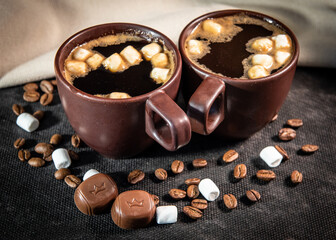 Coffee in brown cups and marshmallows. Coffee break concept. Turkish coffee, marshmallows on a dark background. Close-up. Two cups of coffee with marshmallows, coffee beans