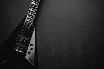 Black and white Top view crop shot of black V shape electric guitar on dark grunge background with...