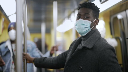 African man face close-up wearing covid-19 face mask inside public transportation underground subway