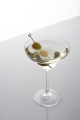 Vermouth in a cocktail glass with olives on a gray background, slightly alcoholic drink