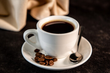 Cup of coffee and coffee beans on a dark background. Side view.