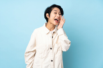 Young Vietnamese woman with short hair over isolated background shouting with mouth wide open