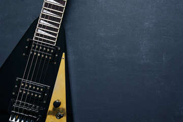 Top view crop shot of black V shape electric guitar on dark grunge background with copy space 