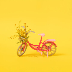 pink modern bibycle with yellow mimosa on illuminating yellow background. minimal decorative concept for summer
