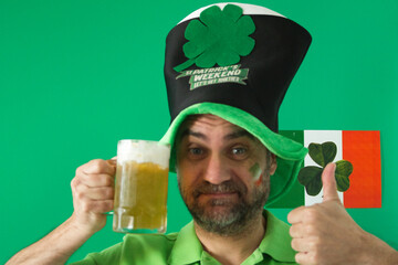 man with mug of fresh beer and hut on green background celebrating saint patrick day