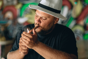 Close up portrait of a man with a beard on his face, wearing black and white panama hat. Adult man...