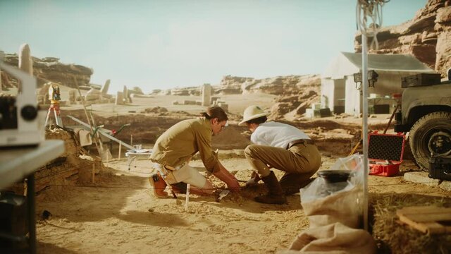 Archaeological Digging Site: Two Great Archeologists Work on Excavation Site, Carefully Lifting Newly Discovered Ancient Civilization Cultural Artifact, Historical Clay Tablet, Fossil Remains