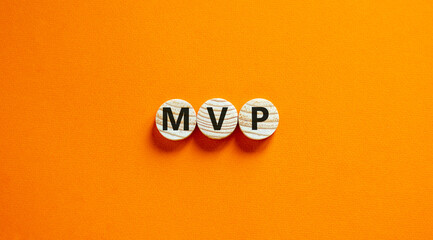 MVP, minimum viable product symbol. Wooden circles with the word MVP, minimum viable product. Beautiful orange background. Business and MVP, minimum viable product concept, copy space.