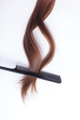a lock of natural hair on a white background is straightened by a brunette and combed by hand with a comb