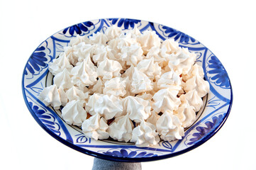 Delicious appetizing Meringue Pavlovas on a plate in woman's hand. Homemade meringues. French dessert, sweet food made by baking a mixture of stiffly beaten egg whites and sugar until crisp. 