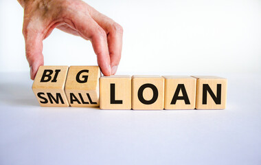 Big or small loan symbol. Businessman turns a wooden cube and changes words 'small loan' to 'big loan'. Beautiful white table, white background, copy space. Business and big or small loan concept.