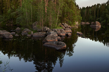typical Finnish landscape - a lake in a pine forest with huge boulders brought here during the Ice...