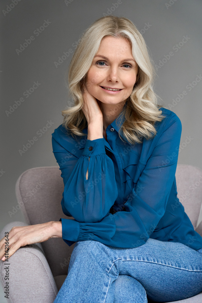 Poster sophisticated smiling elegant beautiful 50s attractive middle aged smiling woman model sitting in ch