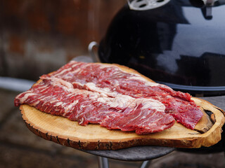Raw hanging tender or onglet steak of beef on wooden Board. Preparing meat for barbecue grilling....