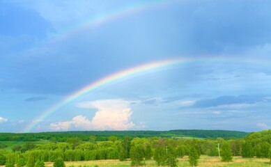 Summer landscape with colorful rainbows, green forest and rural field - 414218889